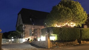 A stone building with a gated entrance, a paved driveway, and a well-maintained hedge. - Domaine Lacoste (Carsac-Aillac)