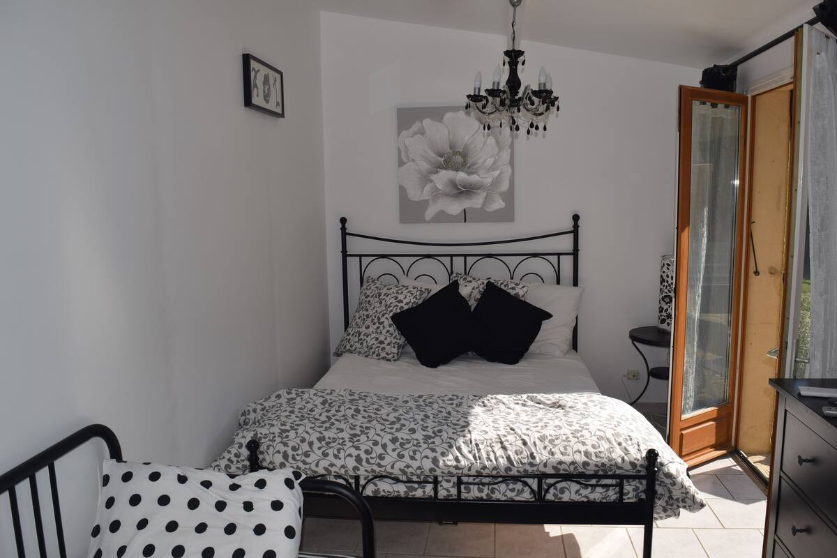 Une chambre à coucher avec un lit, une chaise, une commode et un lustre.