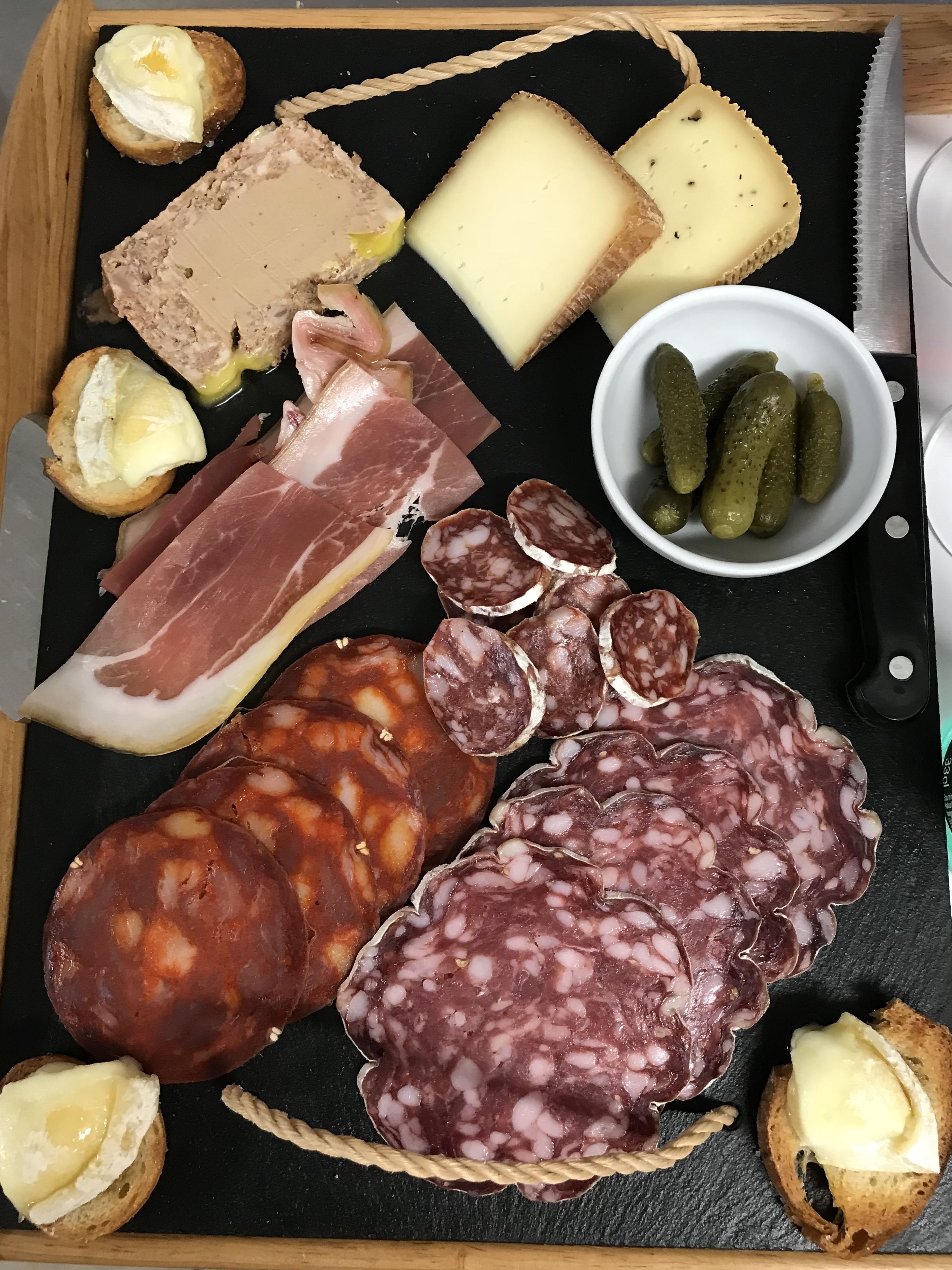 Una tabla de embutidos con diversos tipos de carne, quesos y pepinillos.