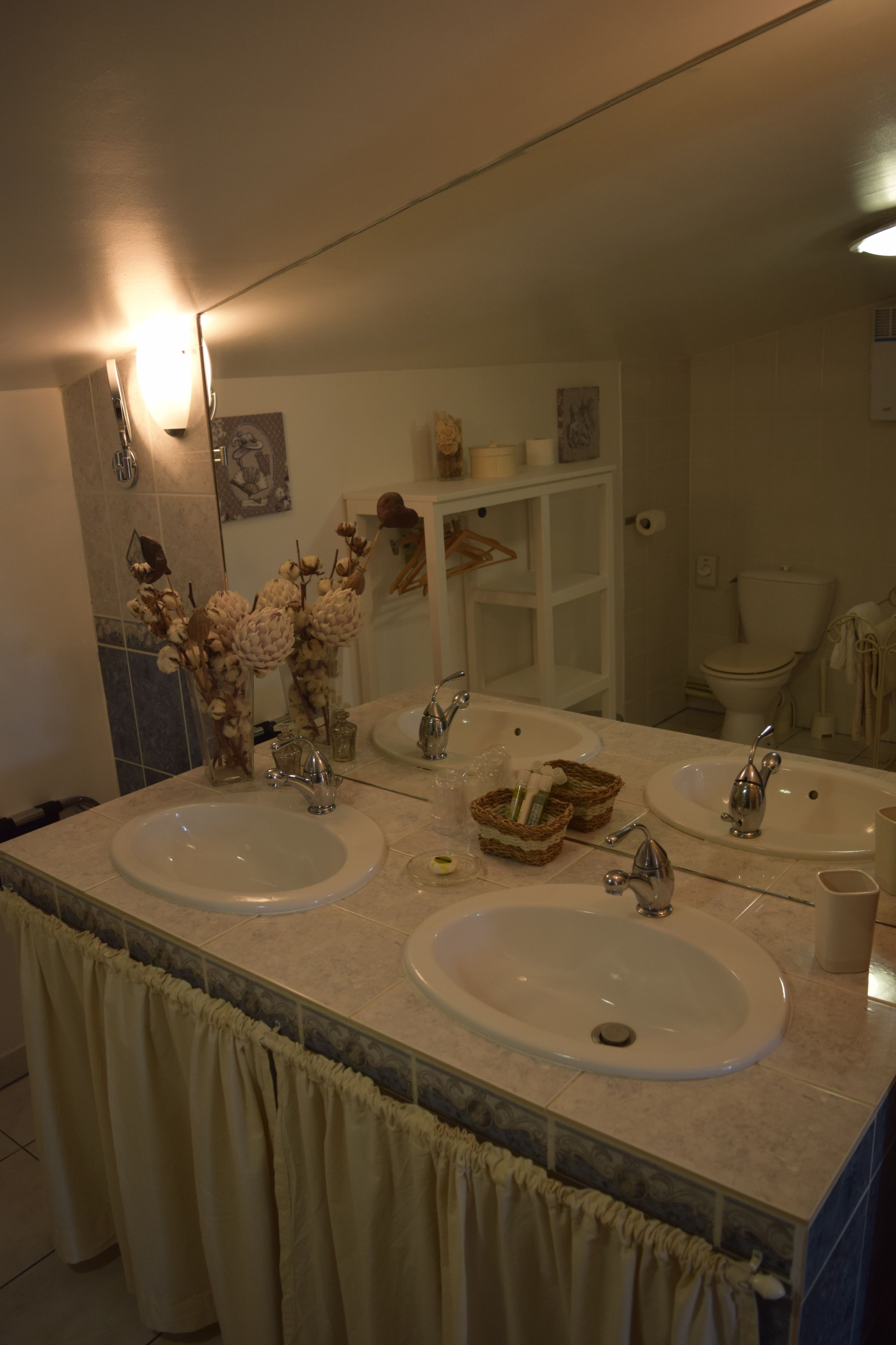 Een badkamer met twee wastafels, een grote spiegel en een toilet.