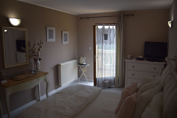 A bedroom with a bed, a dresser, a TV, and a window with curtains. - Domaine Lacoste (Carsac-Aillac)