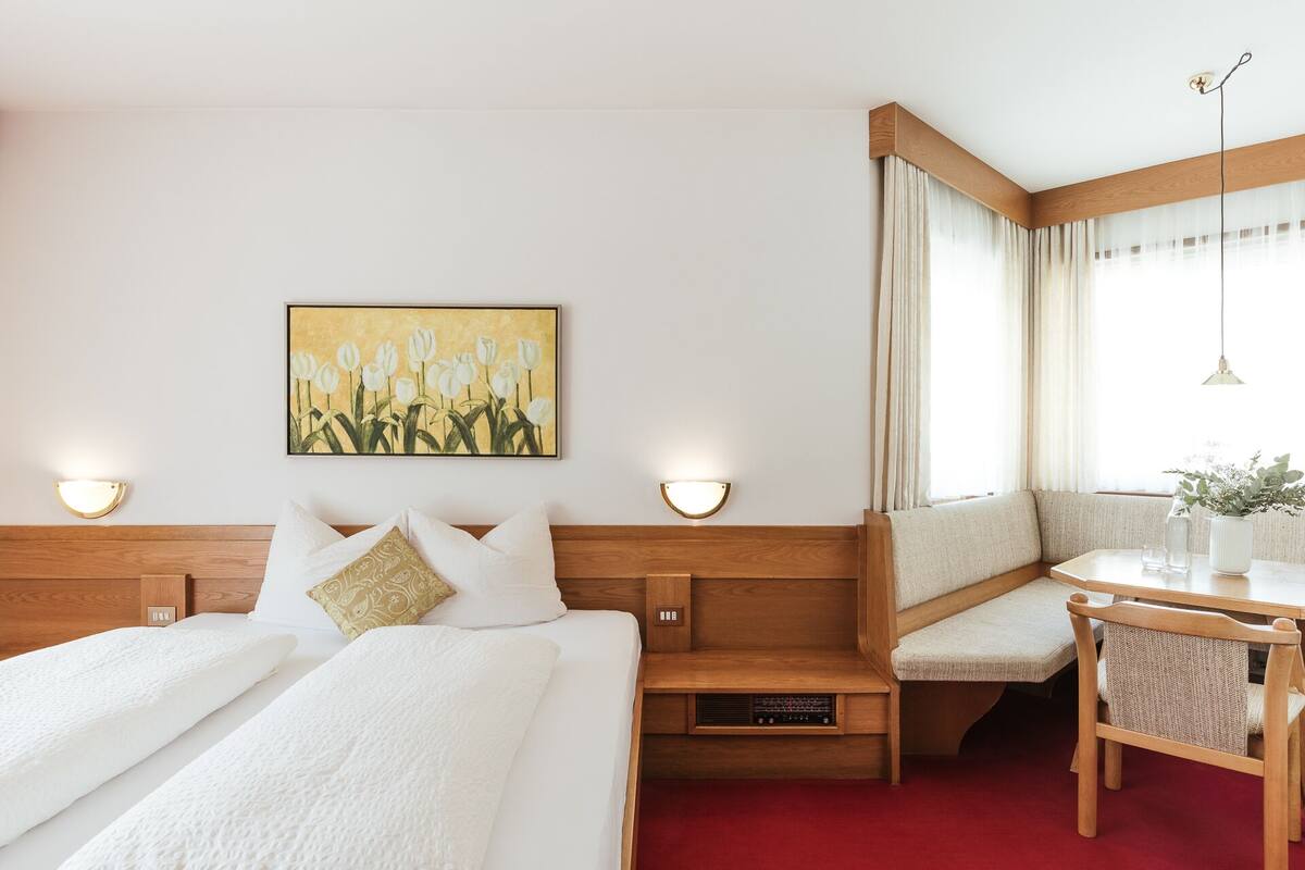 Une chambre d’hôtel avec un lit, un banc, un bureau et un tableau au mur.
