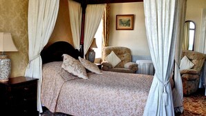 Un lit à baldaquin, une chaise, une table de chevet et un tableau accroché au mur.