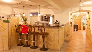A bar area with a stone counter, bar stools, and hanging lights. - Ente von Wassertrüdingen (Wassertruedingen)