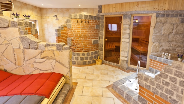 A stone-walled room with a bed, a wooden door, and a small sink. - Ente von Wassertrüdingen (Wassertruedingen)
