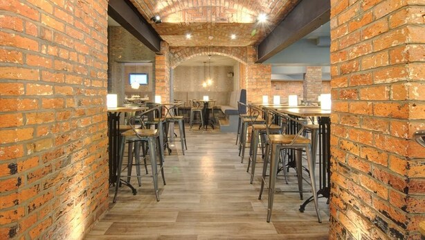 A restaurant with brick walls, wooden flooring, and metal bar stools. - The Royal Hotel Crewe, A BRILLIANT Collection (Crewe)