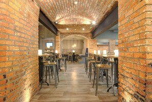 Un restaurante con paredes de ladrillo, piso de madera y taburetes de metal.