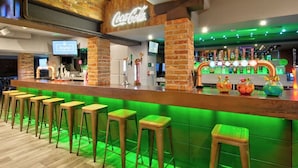 A bar area with a brick wall, green lighting, and a Coca-Cola sign. - The Royal Hotel Crewe, A BRILLIANT Collection (Crewe)