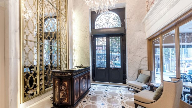 Una hall con pavimento in marmo, una porta nera, un lampadario e un'area salotto con vista.