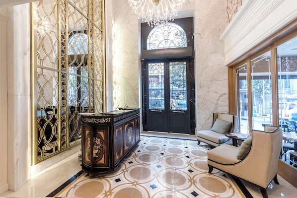 A lobby with a marble floor, a black door, a chandelier, and a seating area with a view.