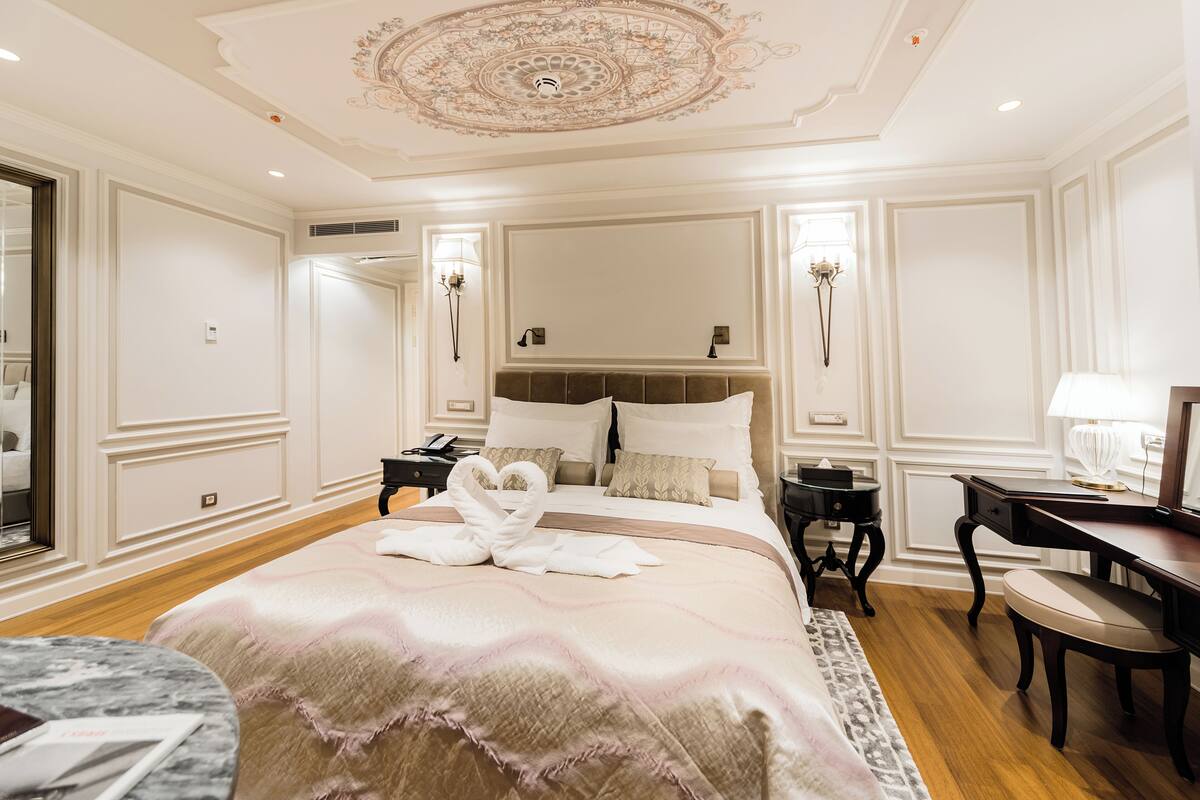 A hotel room with a large bed, a desk, and a chair.