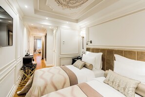 Habitación de hotel con dos camas, televisión, escritorio y vestidor.