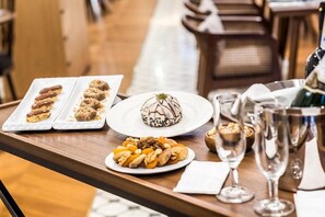 Una mesa con platos de postres, frutos secos y copas de vino.