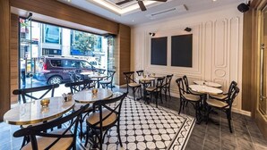 Interno di un ristorante con tavoli rotondi, sedie, una ventola a soffitto e un pavimento decorato.