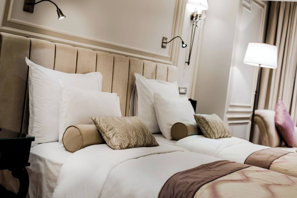 A hotel room with a large bed, two bedside tables, and a wall-mounted lamp.