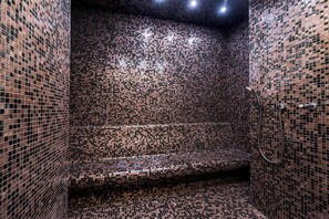 A bathroom with mosaic tile walls and a bench.