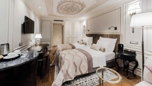 Una camera d'albergo con un letto grande, una scrivania con una lampada, una televisione e un tavolino con una lampada.