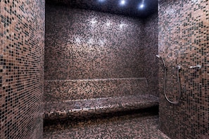 A bathroom with mosaic tile walls and a bench.