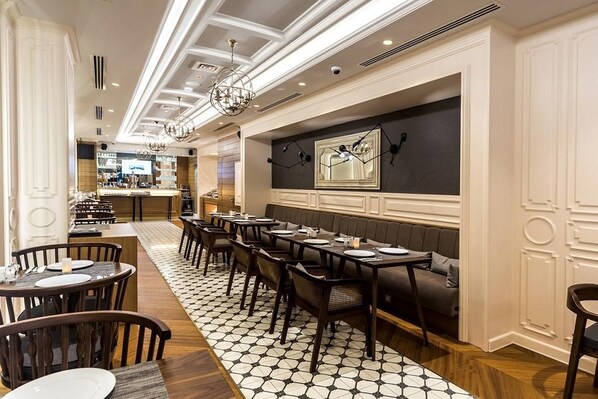 A restaurant with a long dining table, multiple chairs, a bar area, and a patterned floor.