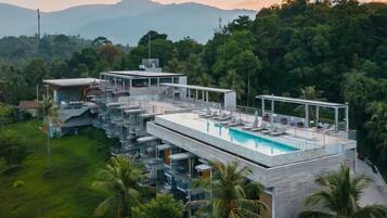 A modern resort with a rooftop pool, multiple balconies, and lush greenery.