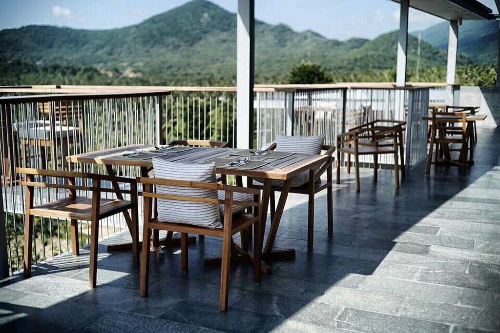 Una terraza con muebles de madera y vistas a colinas verdes.