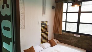 Une chambre à coucher avec un lit, des oreillers, une fenêtre avec des rideaux, une horloge murale et un panneau avec des caractères chinois.