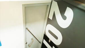 Une porte avec un porte-serviettes et une main courante, et un grand numéro « 201 » sur le mur.