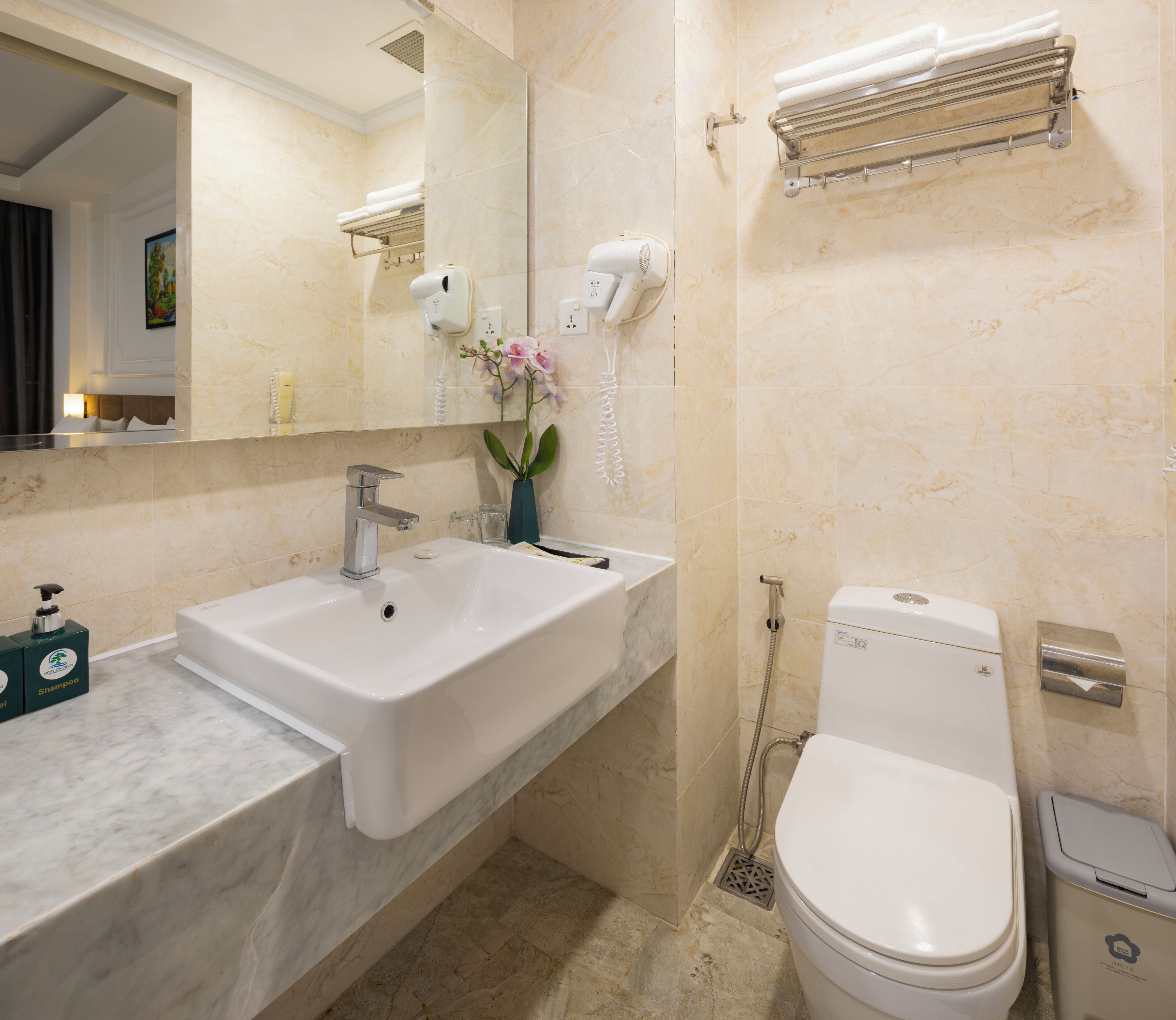 Une salle de bain équipée d’un lavabo, d’un miroir, de toilettes et d’un porte-serviettes.