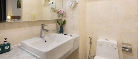 Une salle de bain équipée d’un lavabo, d’un miroir, de toilettes et d’un porte-serviettes.