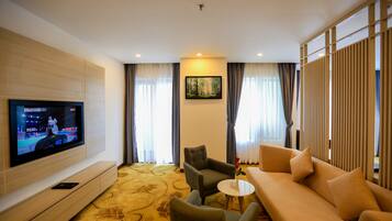 Una habitación de hotel moderna con una televisión de pantalla plana, un sofá, una silla y una mesita.