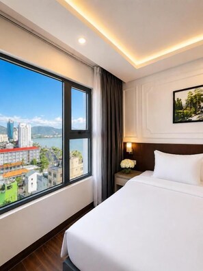 A hotel room with a large window, a bed, a nightstand, and a wall-mounted painting.