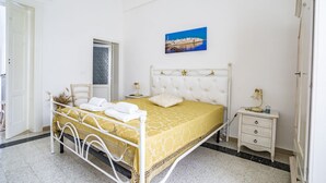 A neatly arranged bedroom with a bed, bedside table, and a wall-mounted picture. - Domus Neptuni (Monopoli)
