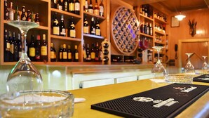 A bar area with shelves of wine bottles, a round wine rack, and a bar mat with a logo.
