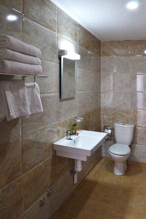 A bathroom with a white sink, a toilet, and a towel rack with folded towels. - Hotel PALACE (Meknes)