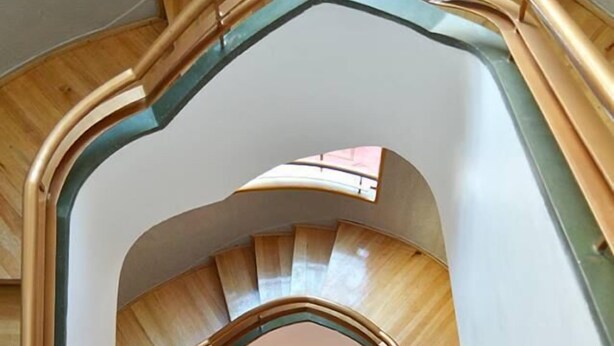 A spiral staircase with a wooden finish and a glass enclosure at the top.