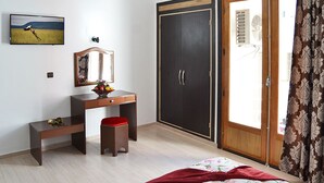 A bedroom with a bed, a desk, a chair, a wardrobe, and a television on the wall.
