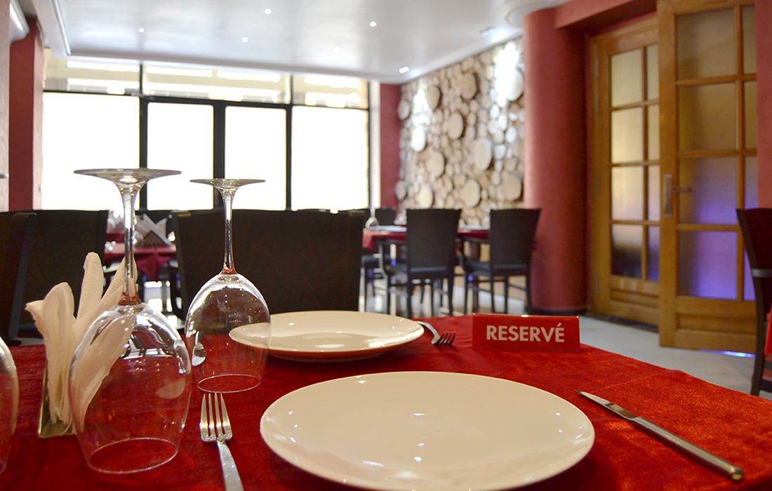 A dining table set with plates, cutlery, and wine glasses, with a 'RESERVÉ' sign indicating a reserved table.