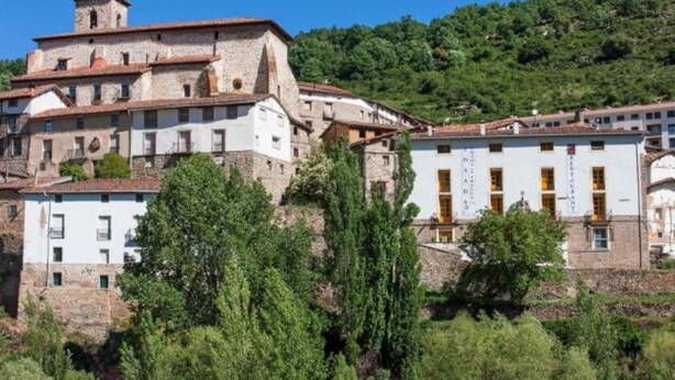 Un edificio histórico de varios niveles, con muros de piedra y una torre destacada.