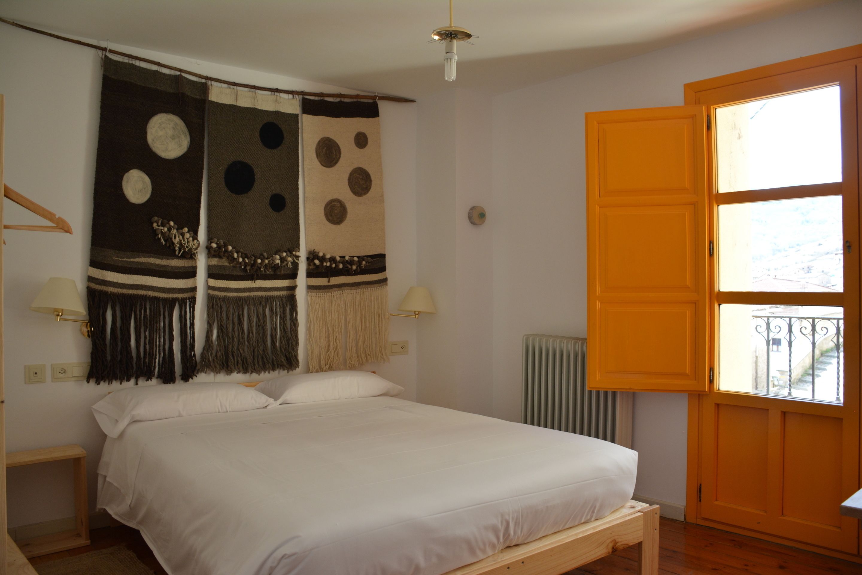 A bedroom with a bed, a large window, and a door.