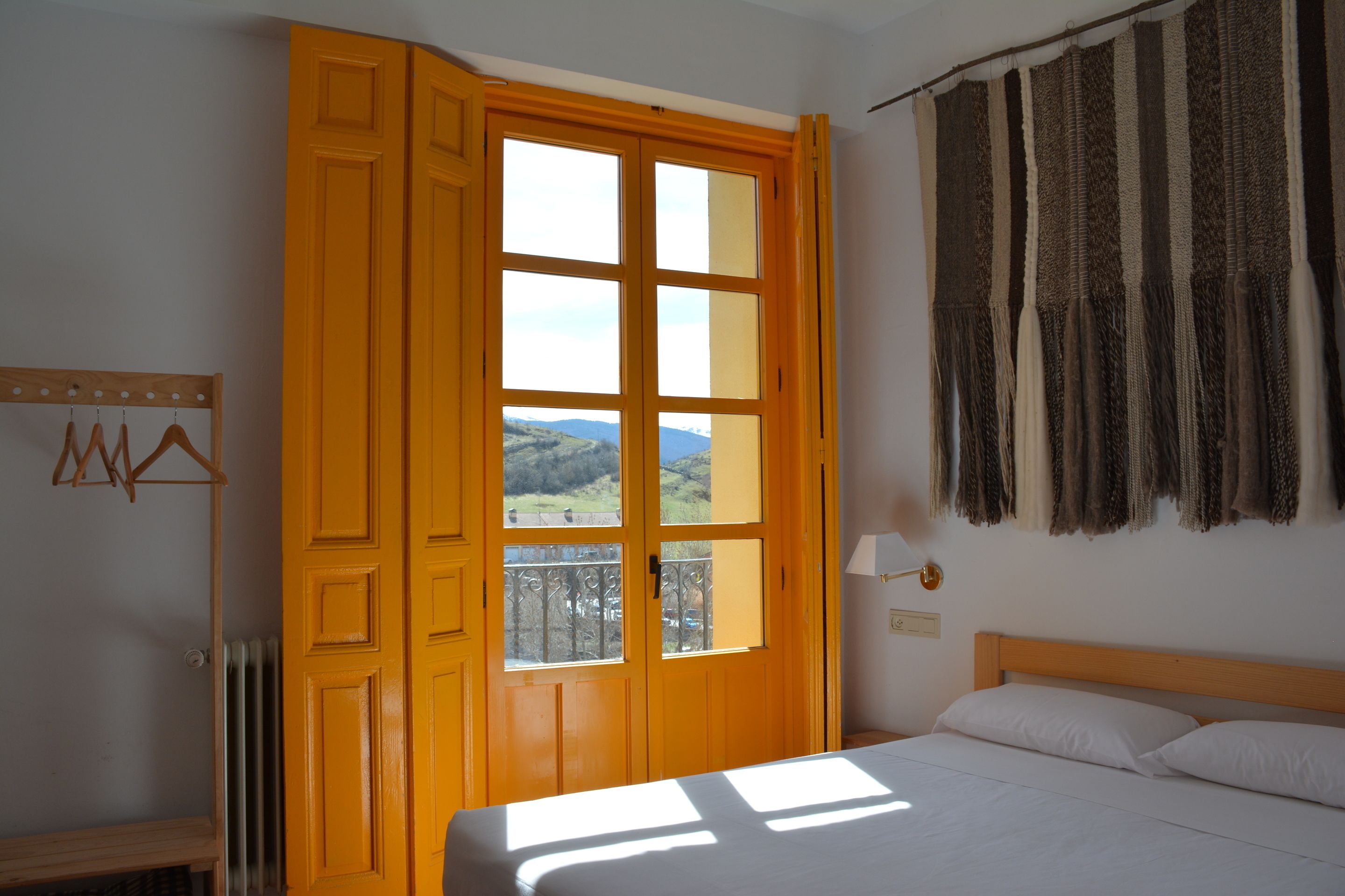 Une chambre avec une grande fenêtre, un lit et une vue sur l’extérieur.