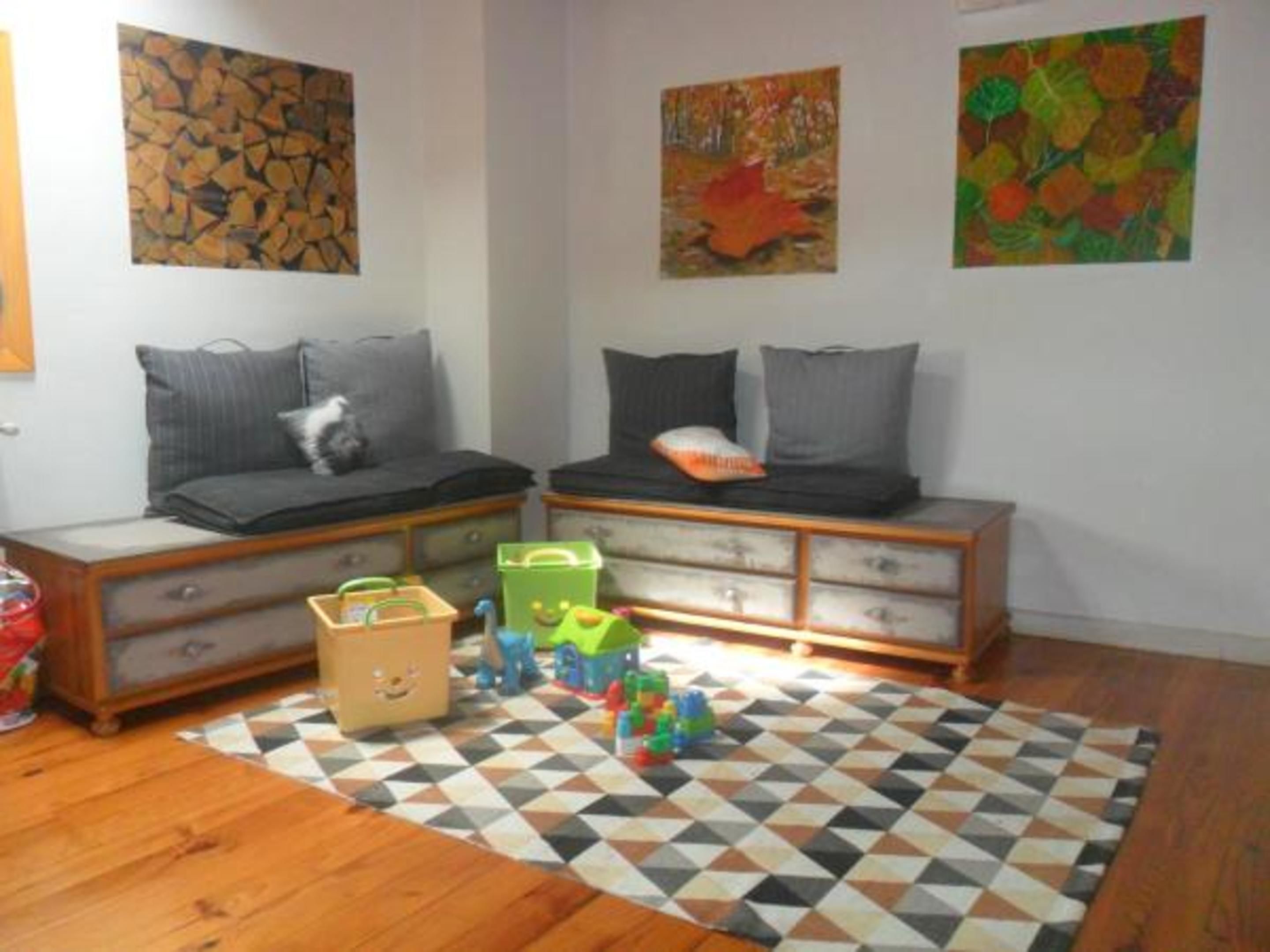 A child's room with two beds, a geometric-patterned rug, and colorful toys.