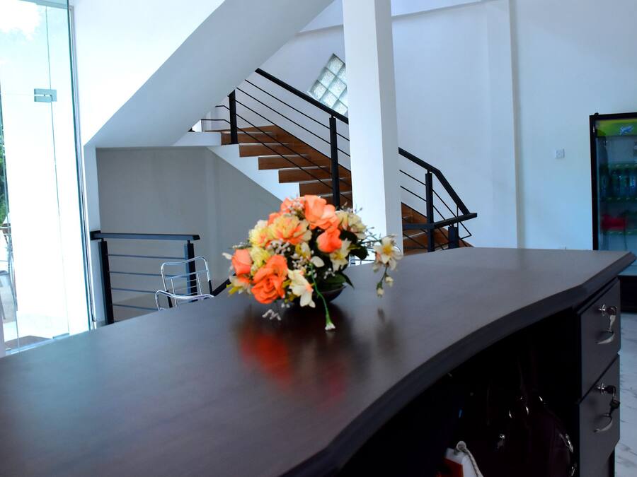 Een modern interieur met een gebogen donkerhouten tafel, een bloevas, een trap en een groot raam.