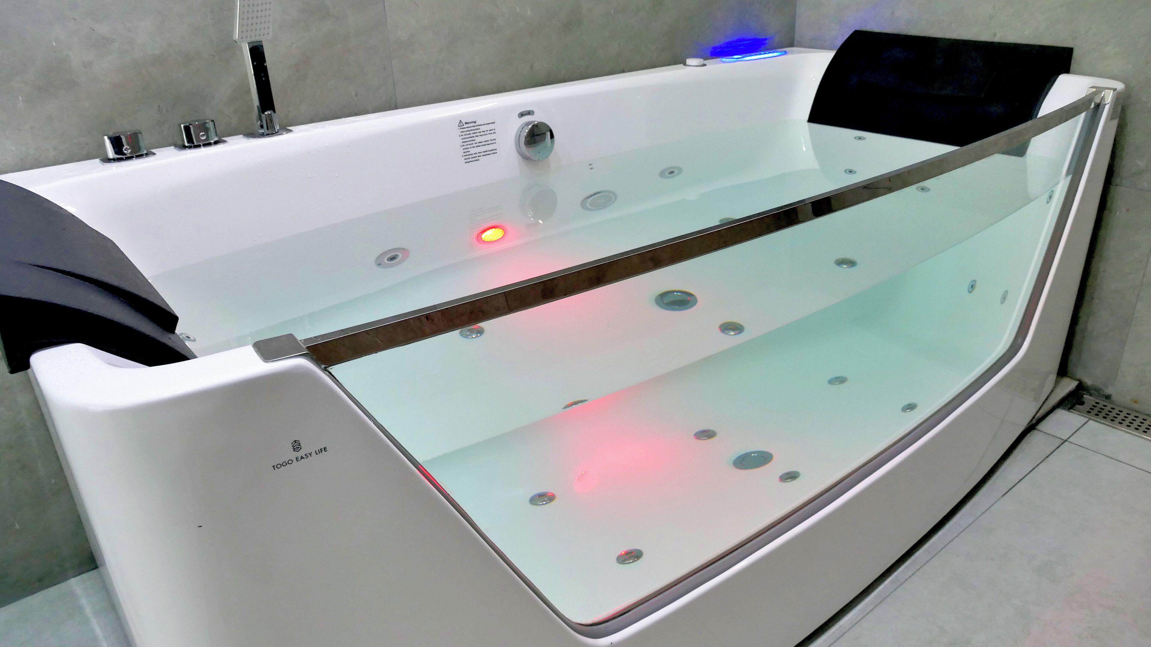 Uma banheira de hidromassagem moderna com divisória de vidro, painel de controle e iluminação LED.