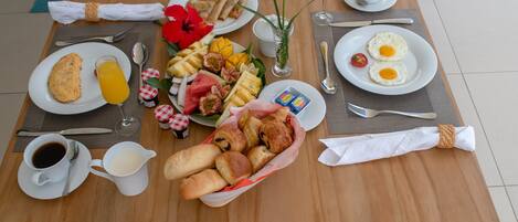 A breakfast table with plates of eggs, toast, and fruit, along with coffee and juice.