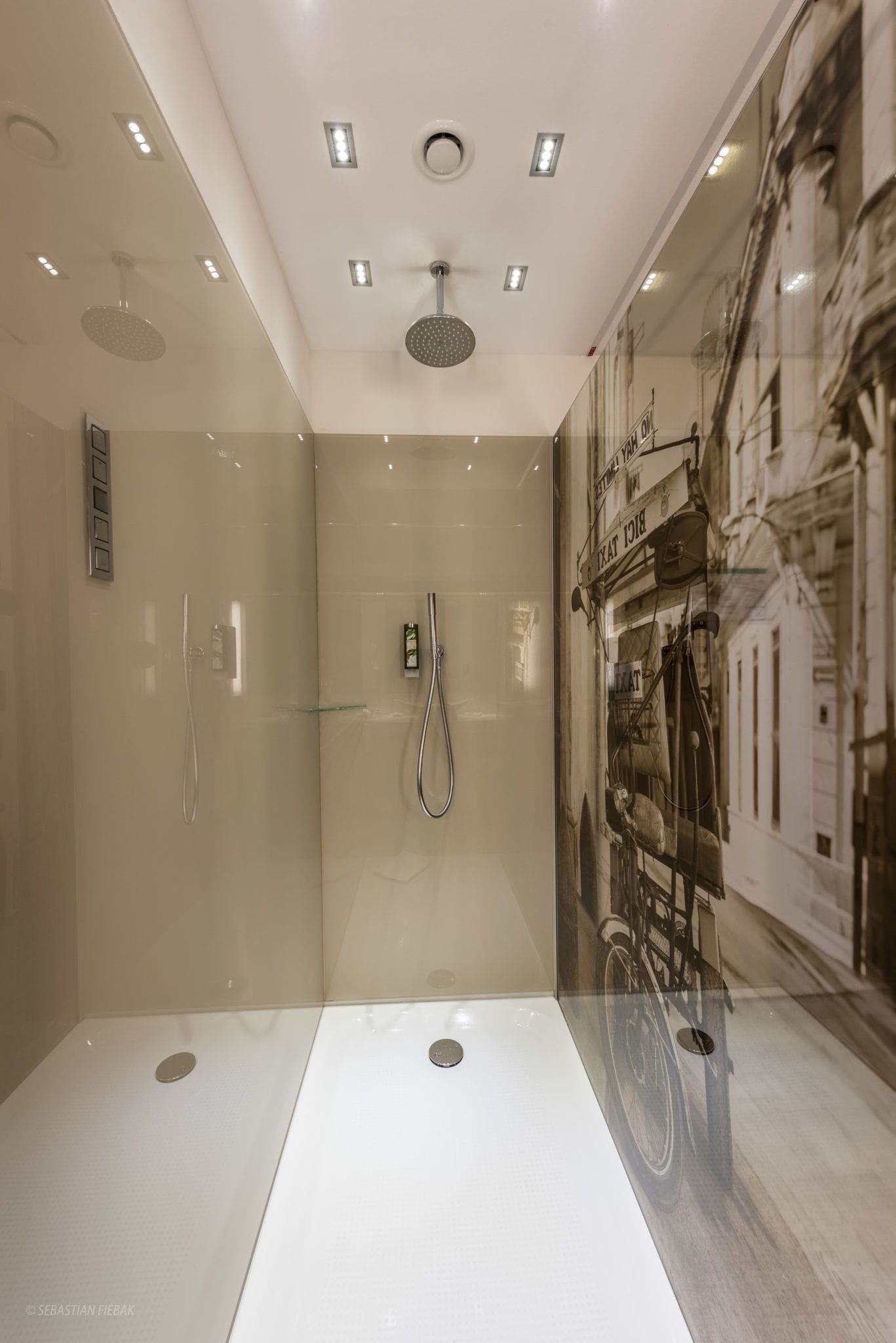 Un baño moderno con cabina de ducha de vidrio, ducha de mano y grifo empotrado.