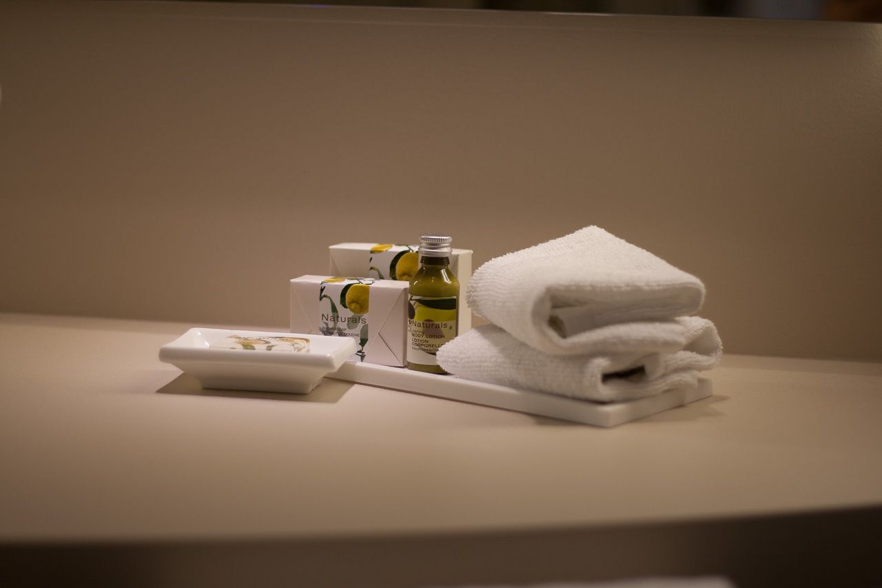 Un baño con una toalla blanca, una botella de loción y un neceser sobre una encimera.