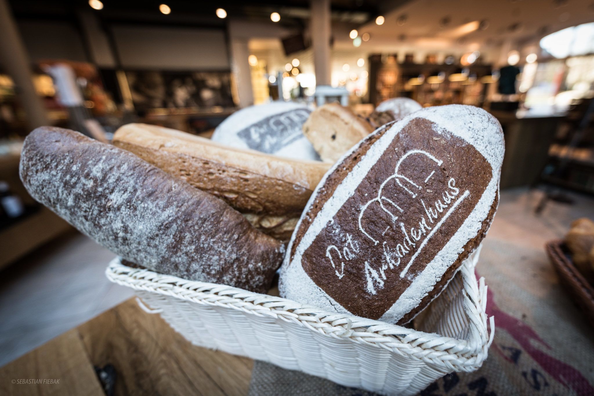 A basket of various breads with a label that reads "Dat Morgen Artisanhaus."