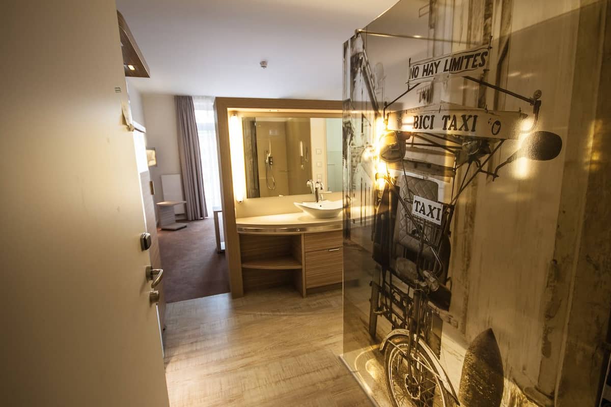 A hotel bathroom with a large mirror, a sink, and a bicycle-themed decoration.