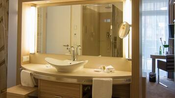 A modern bathroom with a large mirror, two sinks, and a vanity with drawers.