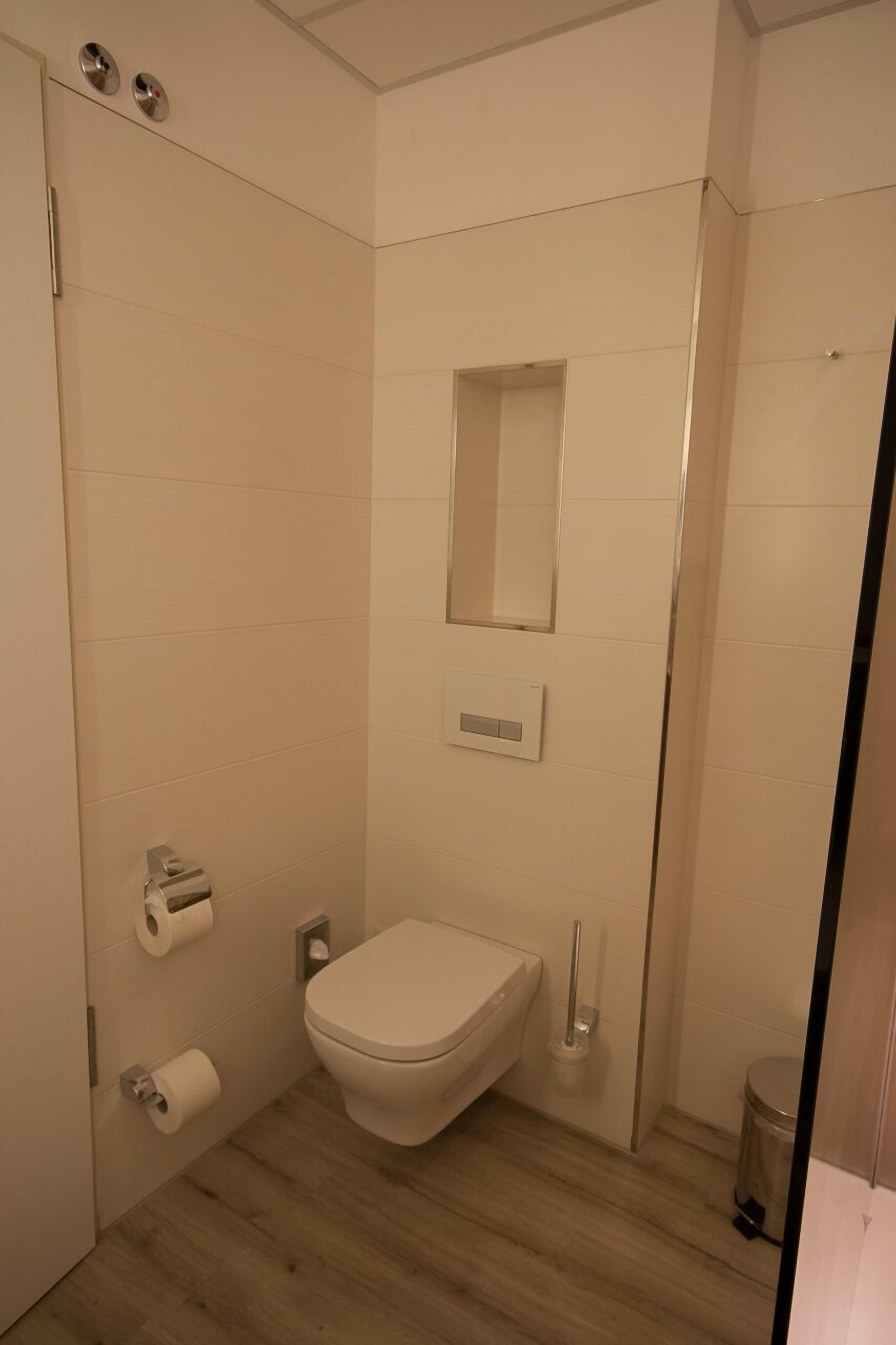 Un baño pequeño y moderno con inodoro, espejo y zona de ducha.